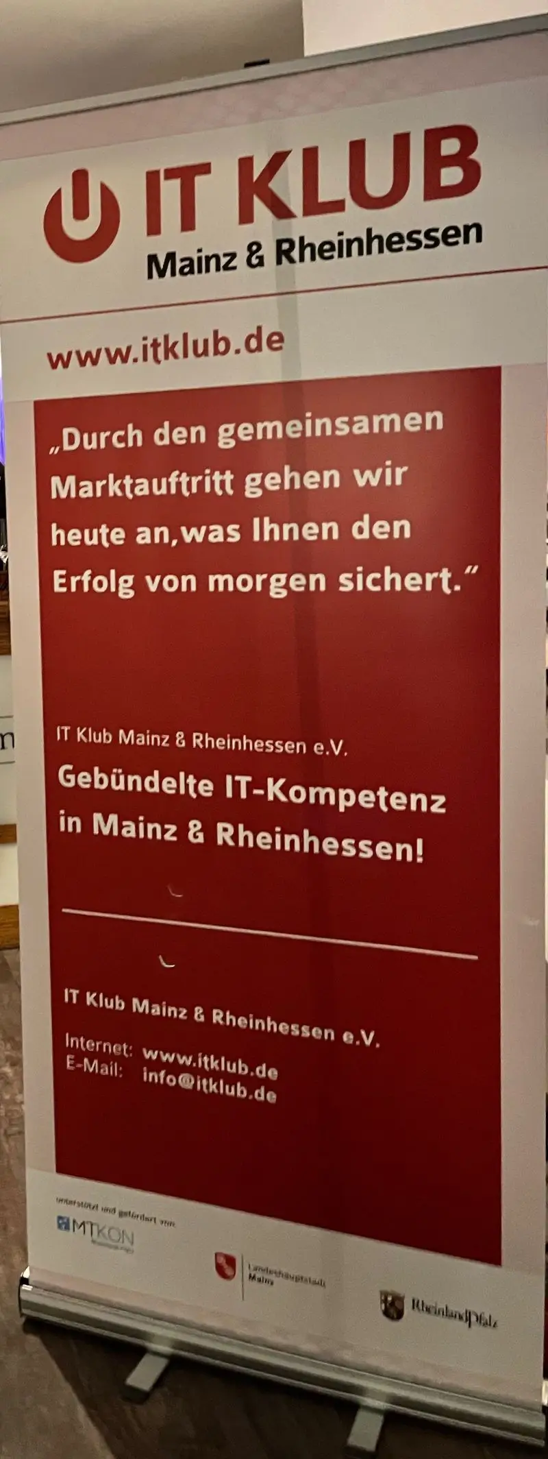 Nahaufnahme eines IT-Klub Aufsteller Banners mit Kontaktdaten und einem Zitat.