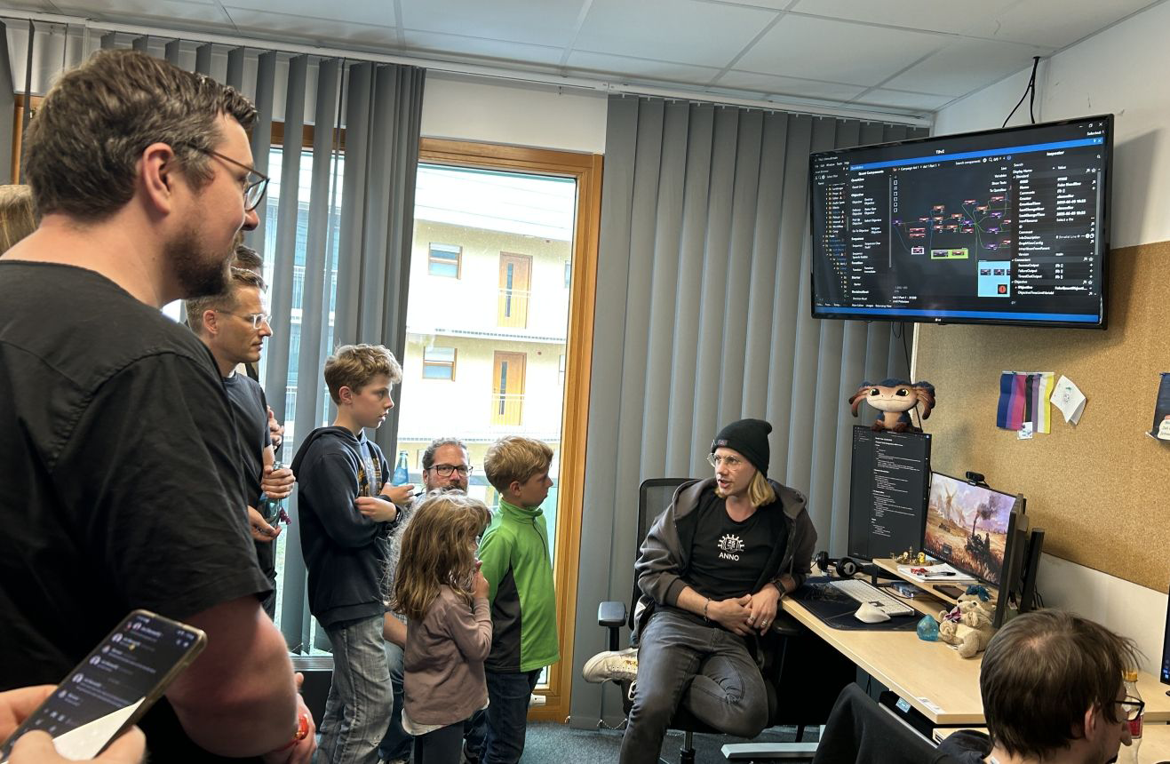 Direkte Einblicke in die Arbeit bei Ubisoft: Eine Gruppe von Menschen steht um einen Schreibtisch herum und hört sich die Erklärungen des Entwicklers an.