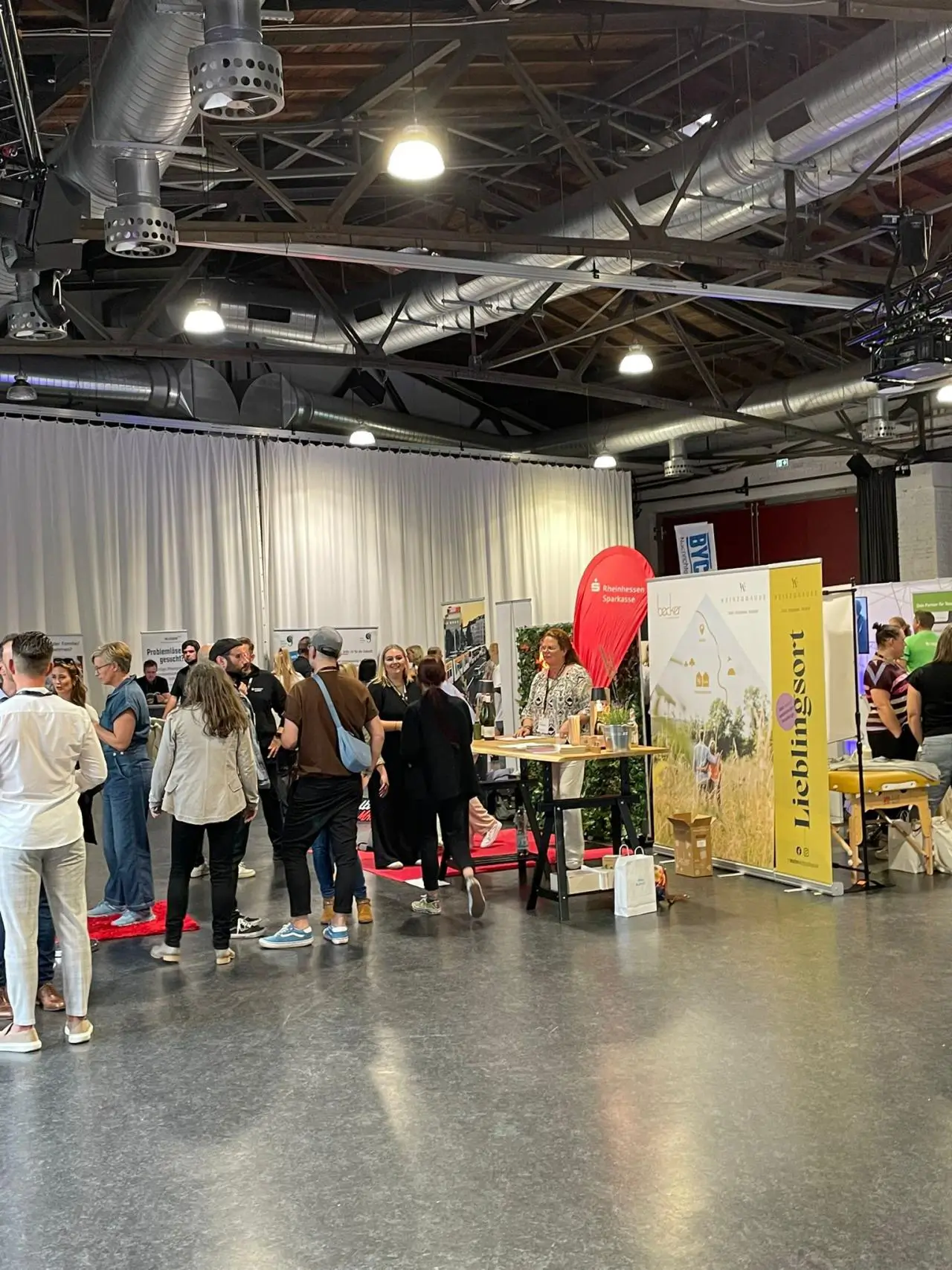 Die Präsentation wird per Beamer an die Leinwand geworfen, in der unteren rechten Ecke sind zwei regenborgenfarbene Ballons platziert, die zusammen die Zahl 50 zeigen.