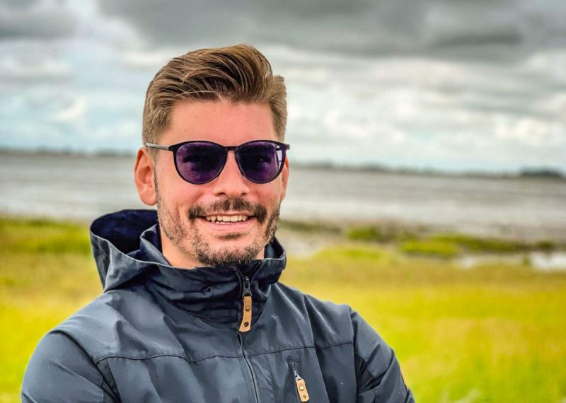 Jonas Niebergall Outdoor mit Sonnenbrille und Regenjacke